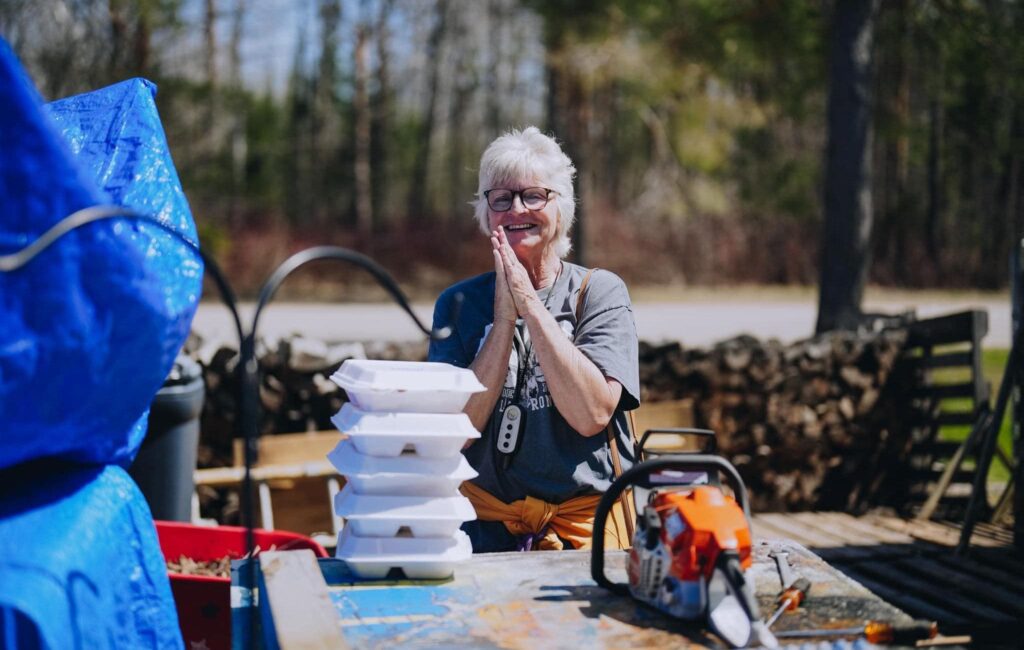 Smiling woman next to stack of to-go meal packages
